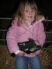 [A girl enjoys cuddling a piglet]